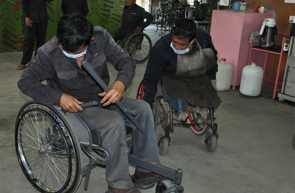 Two technicians from the Veteran's International wheelchair workshop try out the leveraged freedom chair and provide valuable feedback. Photo: Carolina Kaelin