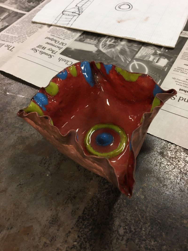 The inside of my cup after enamelling: the main part is copper red and the wall squiggles and chased part are bright blue and green.