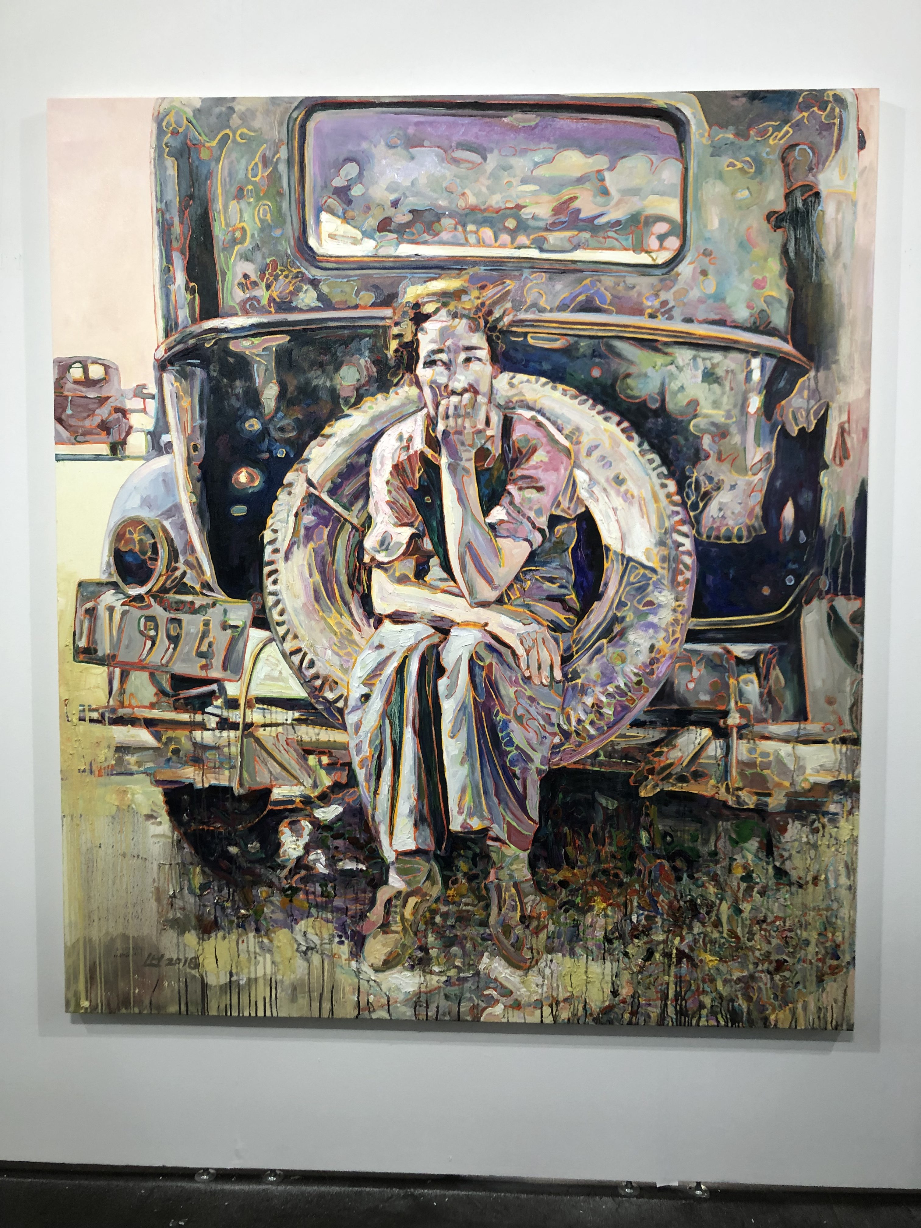 a painting of a person in thought sitting on the spare tire perched to the back of a car (painted very stylistically with many colors)