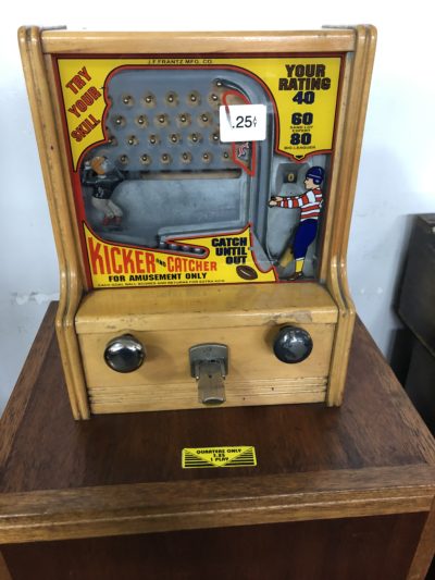 a vintage quarter game where a metal ball is kicked up from the bottom right corner, and then goes through prongs on the way down. To win the ball must be caught in the basket.