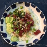 An aesthetically framed bowl of poke (rice, tuna, scallion, cucumber, sesame seeds).