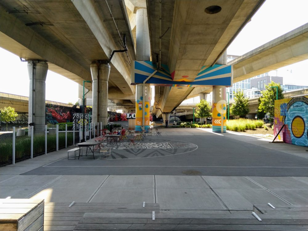 underneath the highway. there are some more murals, some chairs and tables too.