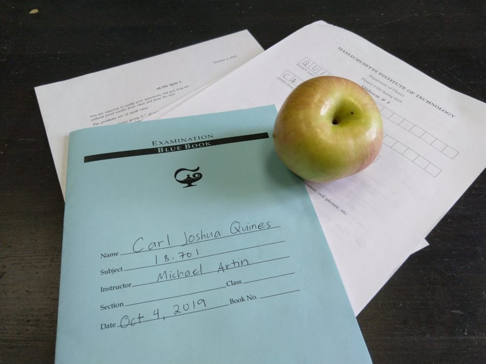 an apple, an exam blue book, a midterm on the back