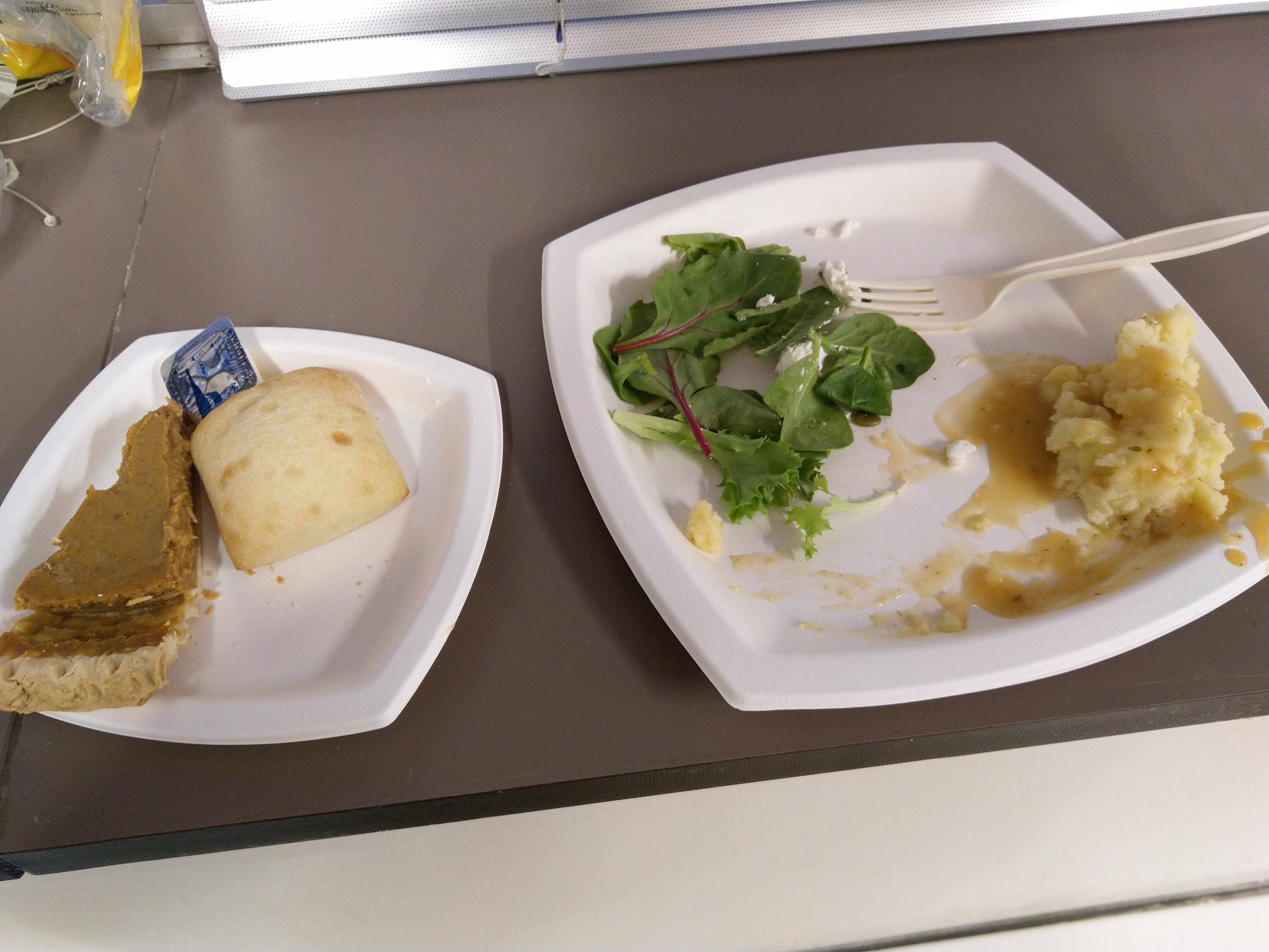 half-finished salad, mashed potato, pumpkin pie, and bread, and a fork, and butter, welp