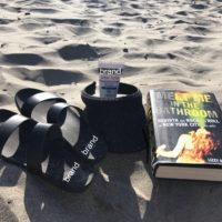 the book meet me in the bathroom lying on the sand at the beach