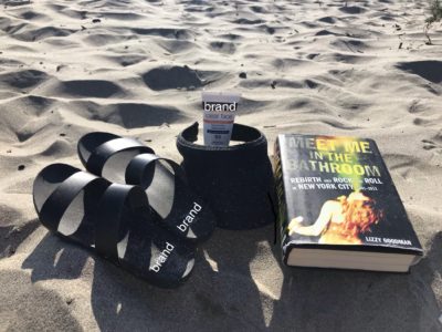 the book meet me in the bathroom lying on the sand at the beach
