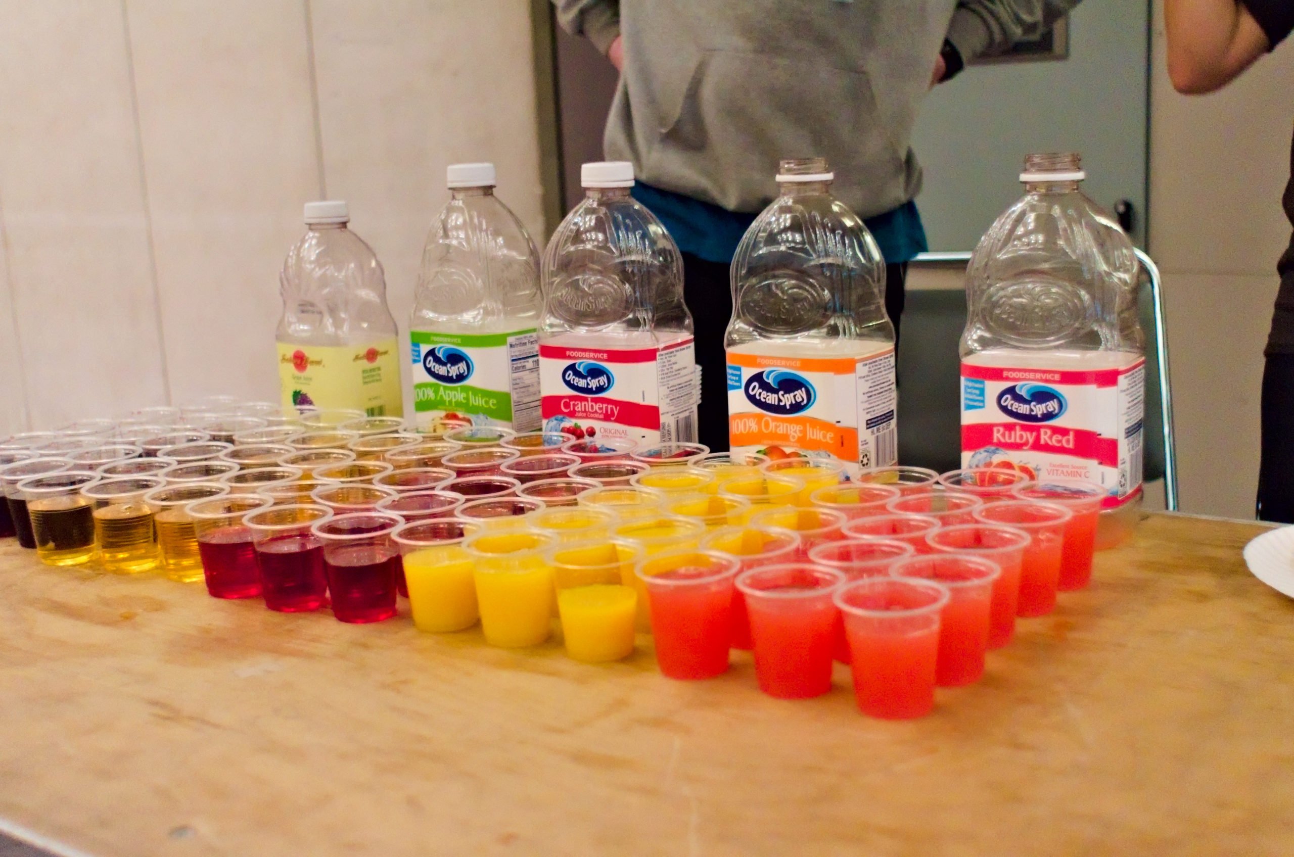 various juices laid out in tasting cups on a table.