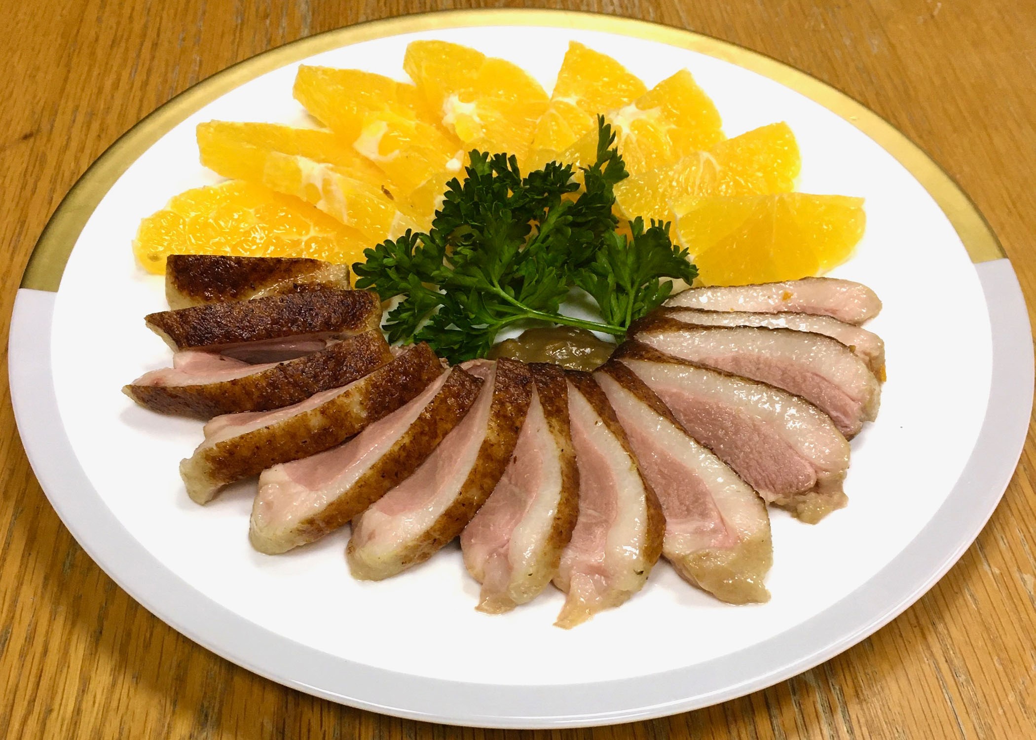 a plate with duck slices and oranges and some sort of vegetable garnish in the middle