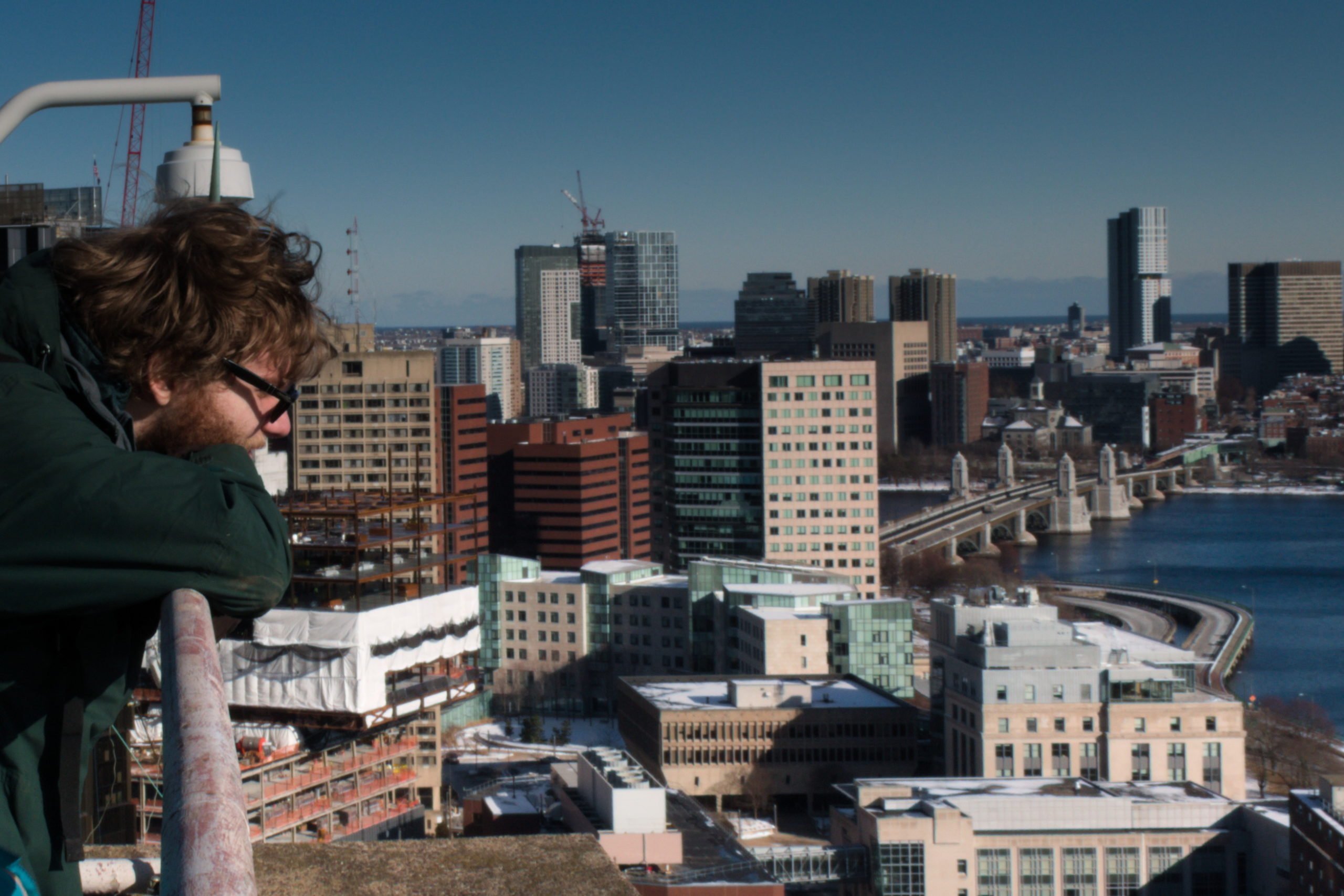A member of the radio society looking out over the roof. Kendall Square and the eastern section of MIT are visible.