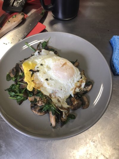 A plate with sautéed vegetables and a fried egg on top