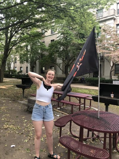 Me standing next to the East Campus flag, smiling 