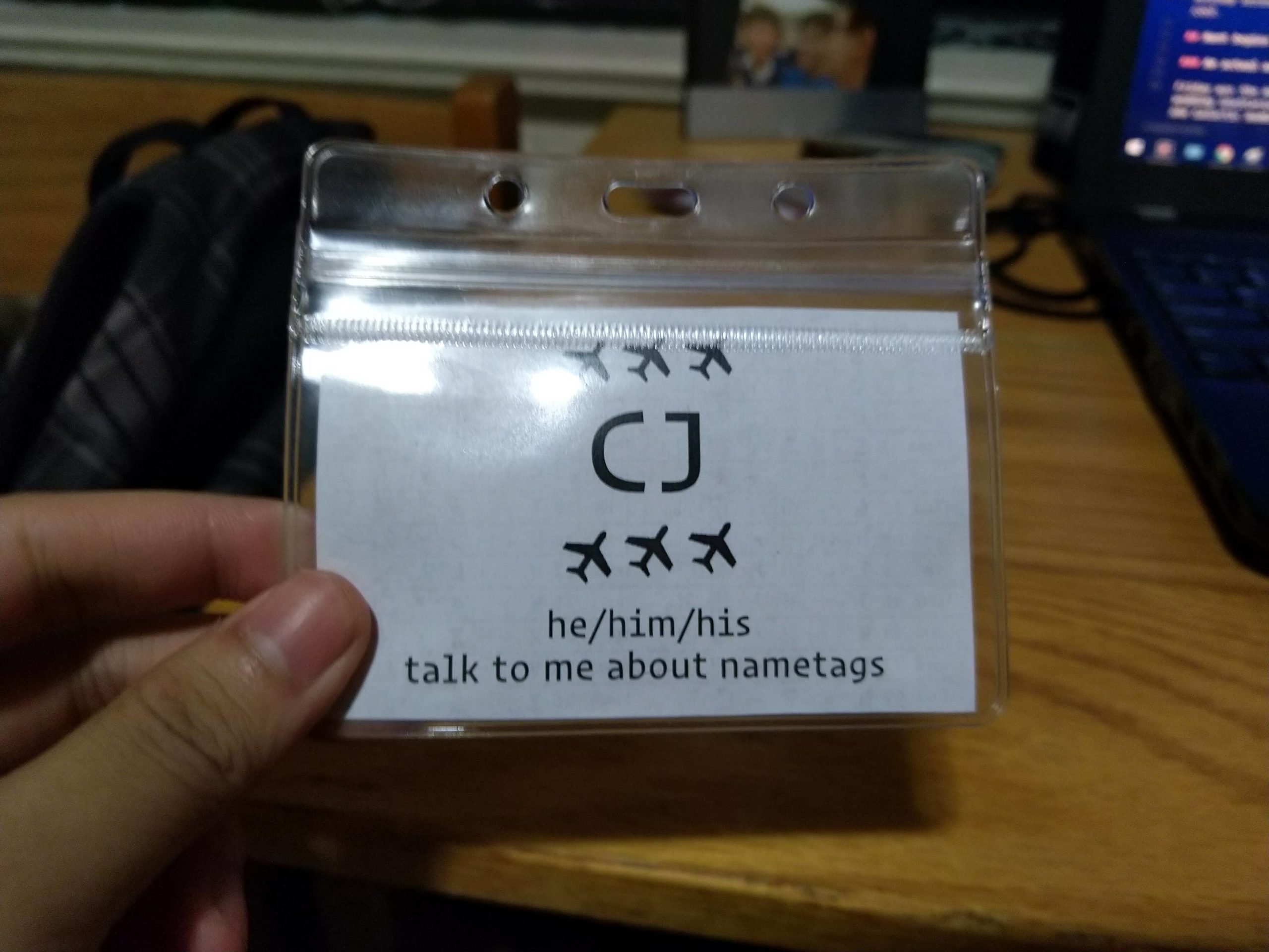 nametag; has three planes, CJ, he/him/his, and “talk to me about nametags”