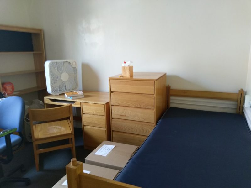 a bare mattress, an empty desk, two boxes on the floor