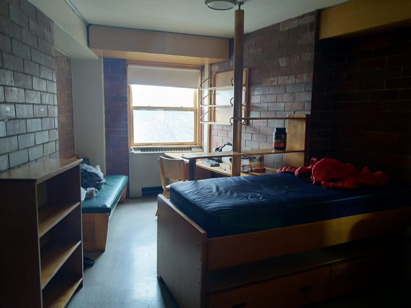 the new room in baker. there's a bed, a cabinet, a desk behind the bed.