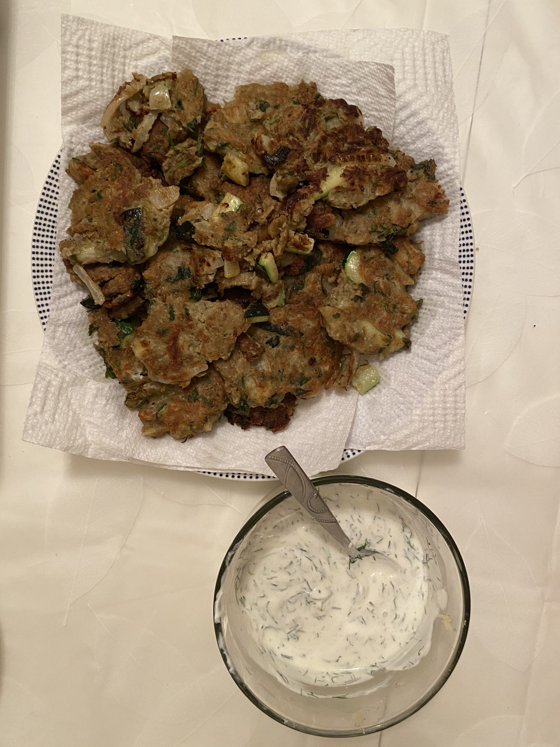 lentil zucchini fritters next to a bowl of yogurt sauce