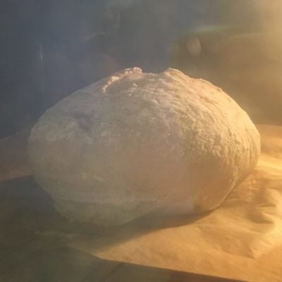 My loaf of bread in the oven. It's blurry, beige, and puffed-up looking.