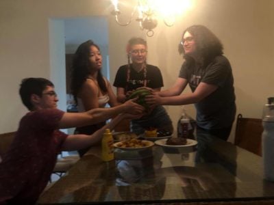 my roommates gathered around our dinner table cradling a watermelon