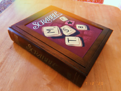 A wooden box holding the board and pieces of the scrabble game.