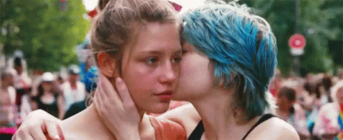 a GIF from Blue is the Warmest Color, showing a blue haired girl kiss her girlfriend on the cheek