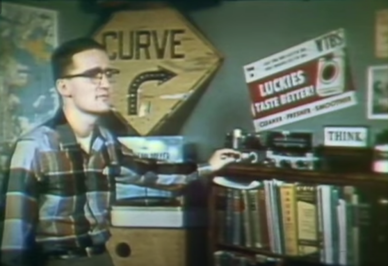 student stands in dorm room with road sign