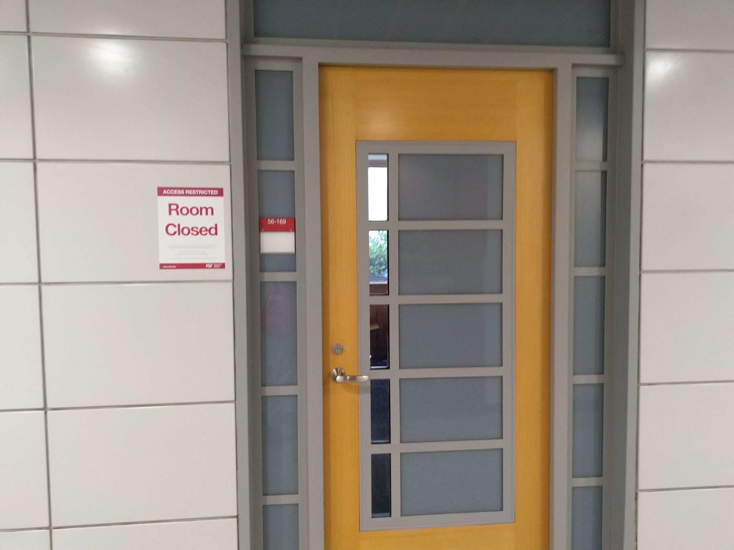 a closed door to a classroom with a Room Closed sign beside it