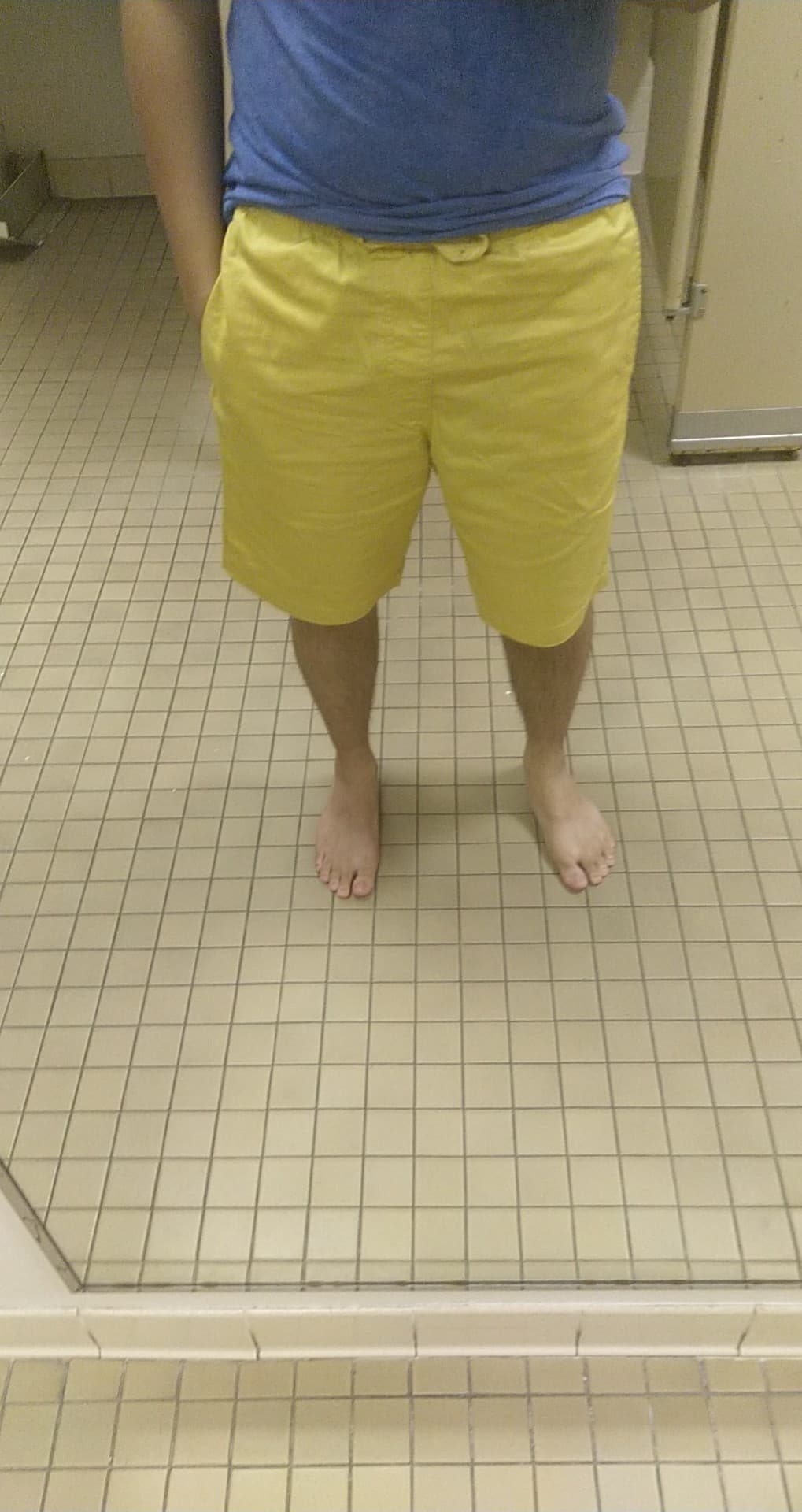 a picture of my lower body in the mirror. i'm barefoot, and wearing bright yellow shorts