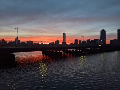 orange rises higher over the boston skyline and the harvard bridge