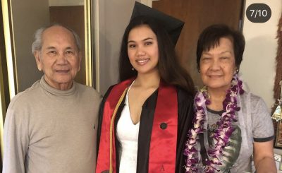 me wearing my graduation robe and cap with my grandparents