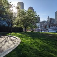 picture of green space in front of water and boston skyline at sunset