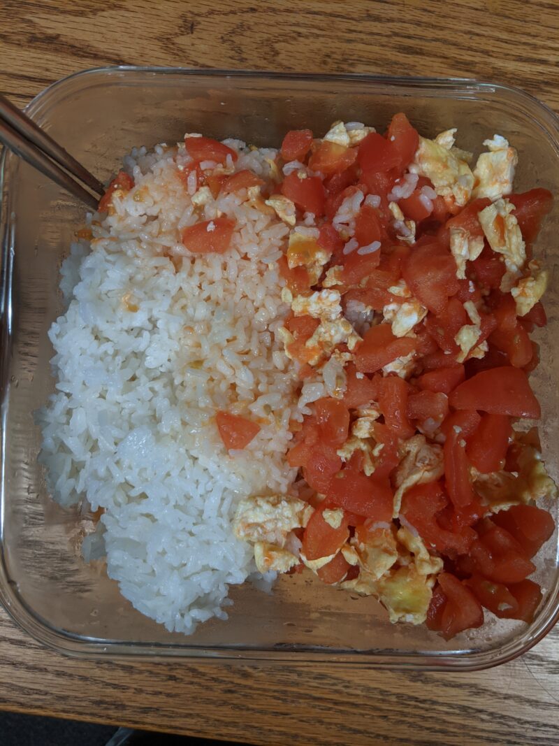 tupperware containing rice on the left and stir-fried tomatoes and eggs on the right