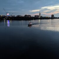 boat moving across the Charles River at sunset