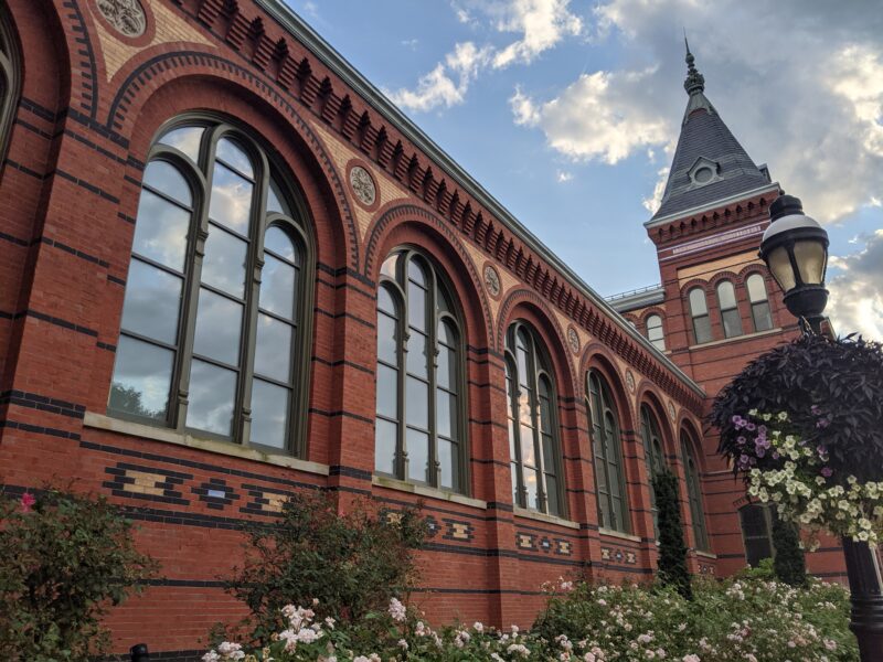 fancy, red and yellow brick building, with nice windows and some bushes on the side