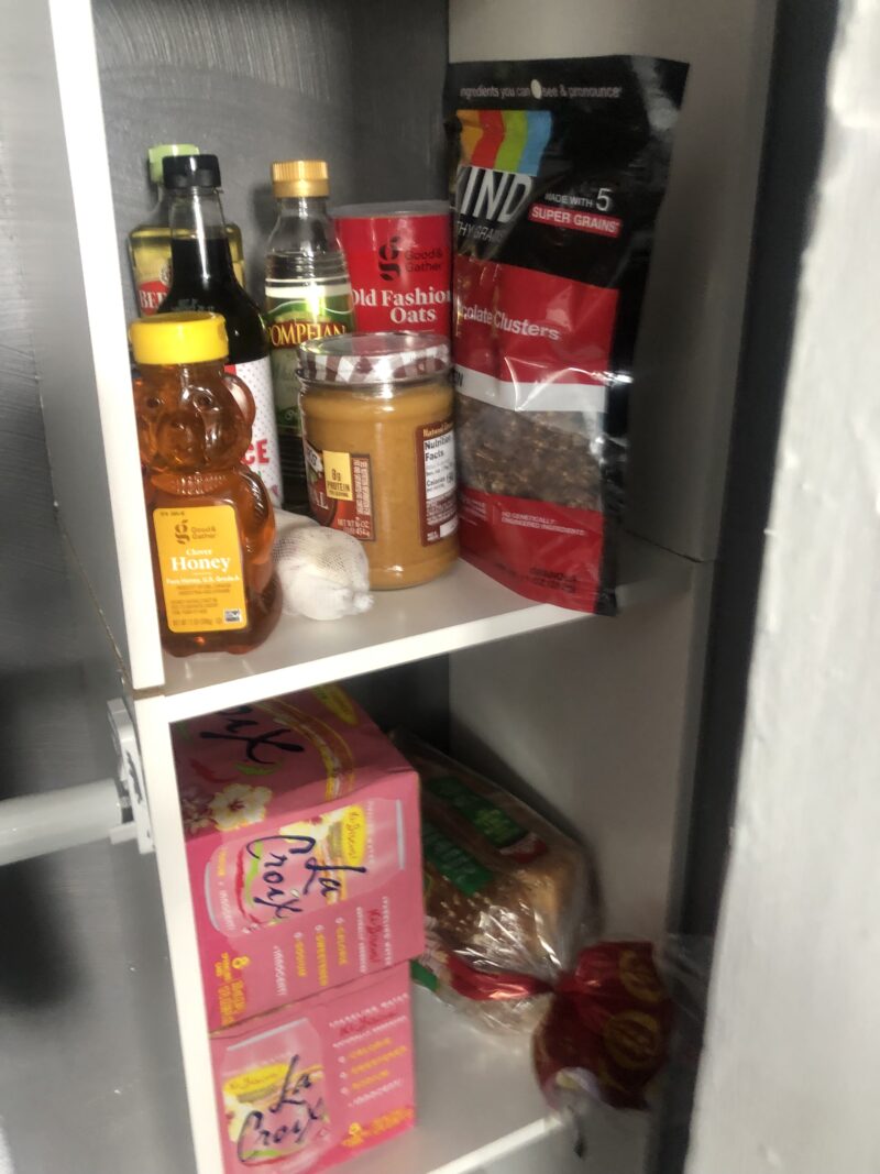 makeshift pantry made out of closet space housing various pantry foods like sauces, rice, granola, bread, etc.