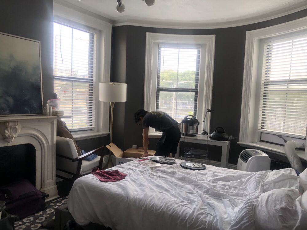 picture of whole room (bed, fake fireplace, chairs, desk-turned-countertop, ac, and three windows all in frame)