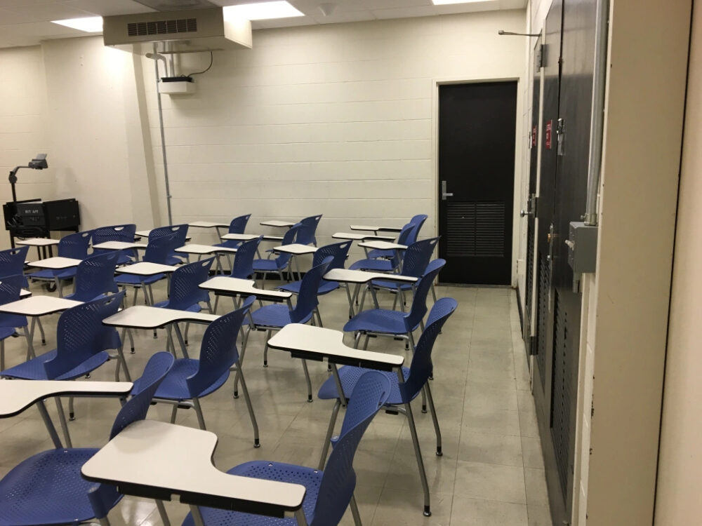 classroom, white walls, three black doors behind