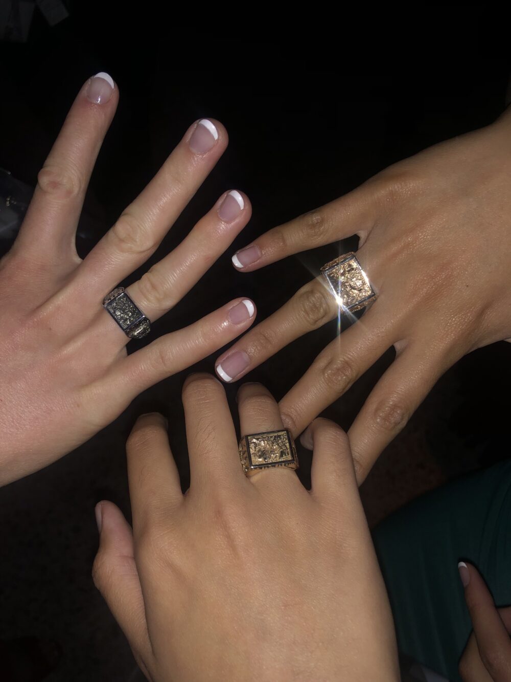 three hands with 2023 brass rats on their ring fingers