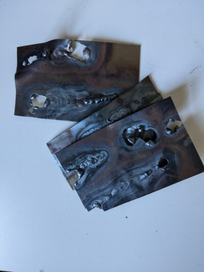 small pieces of metal with messy welding and several holes burned through the metal