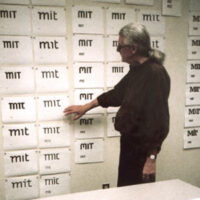 matthew carter standing in front of wall of various mit logo possibilities