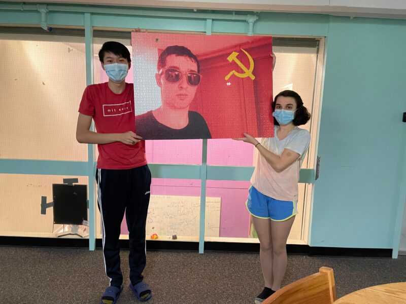 two people holding up a puzzle of a person with a communist filter