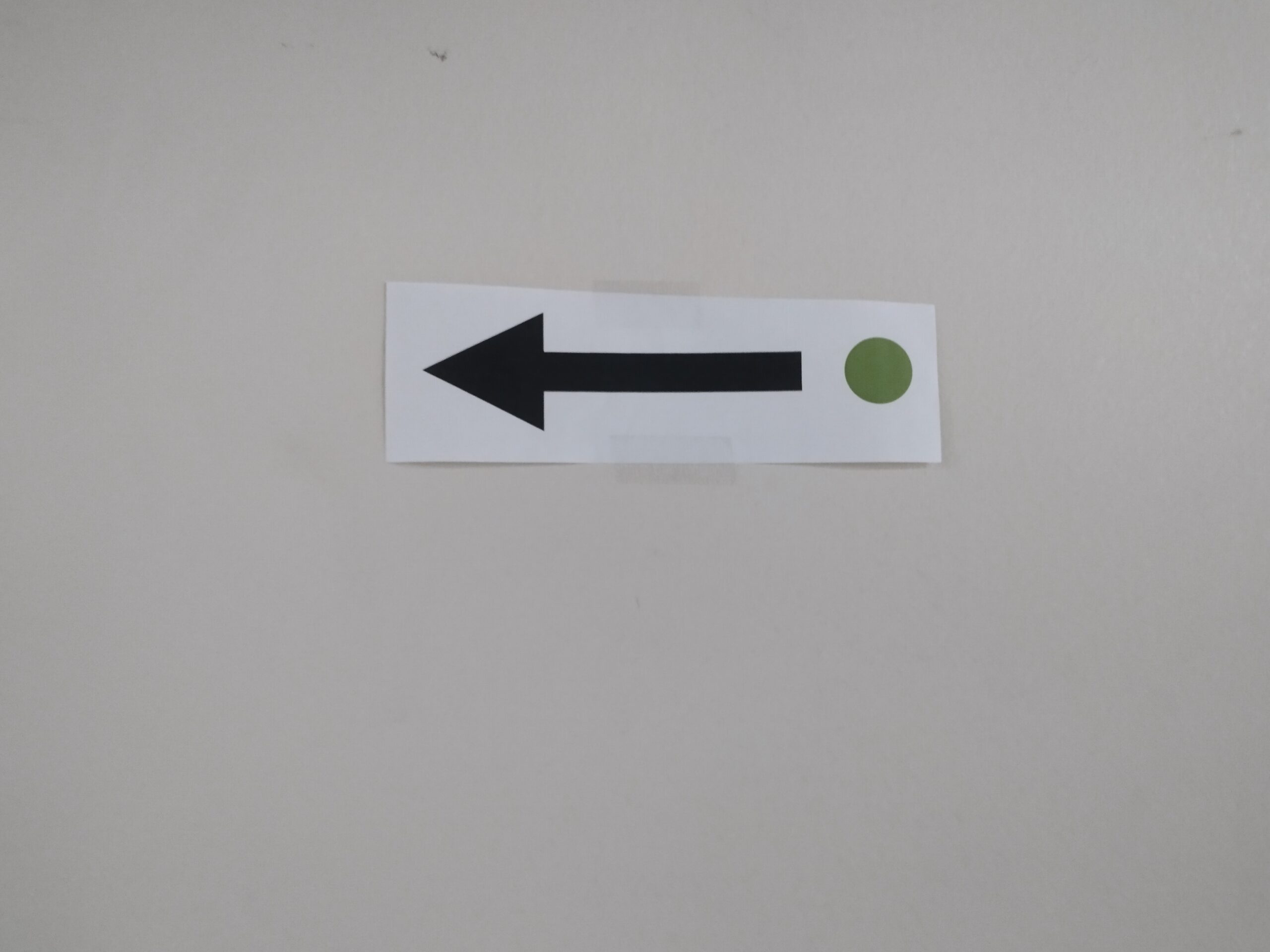 an arrow with a green circle taped to a wall