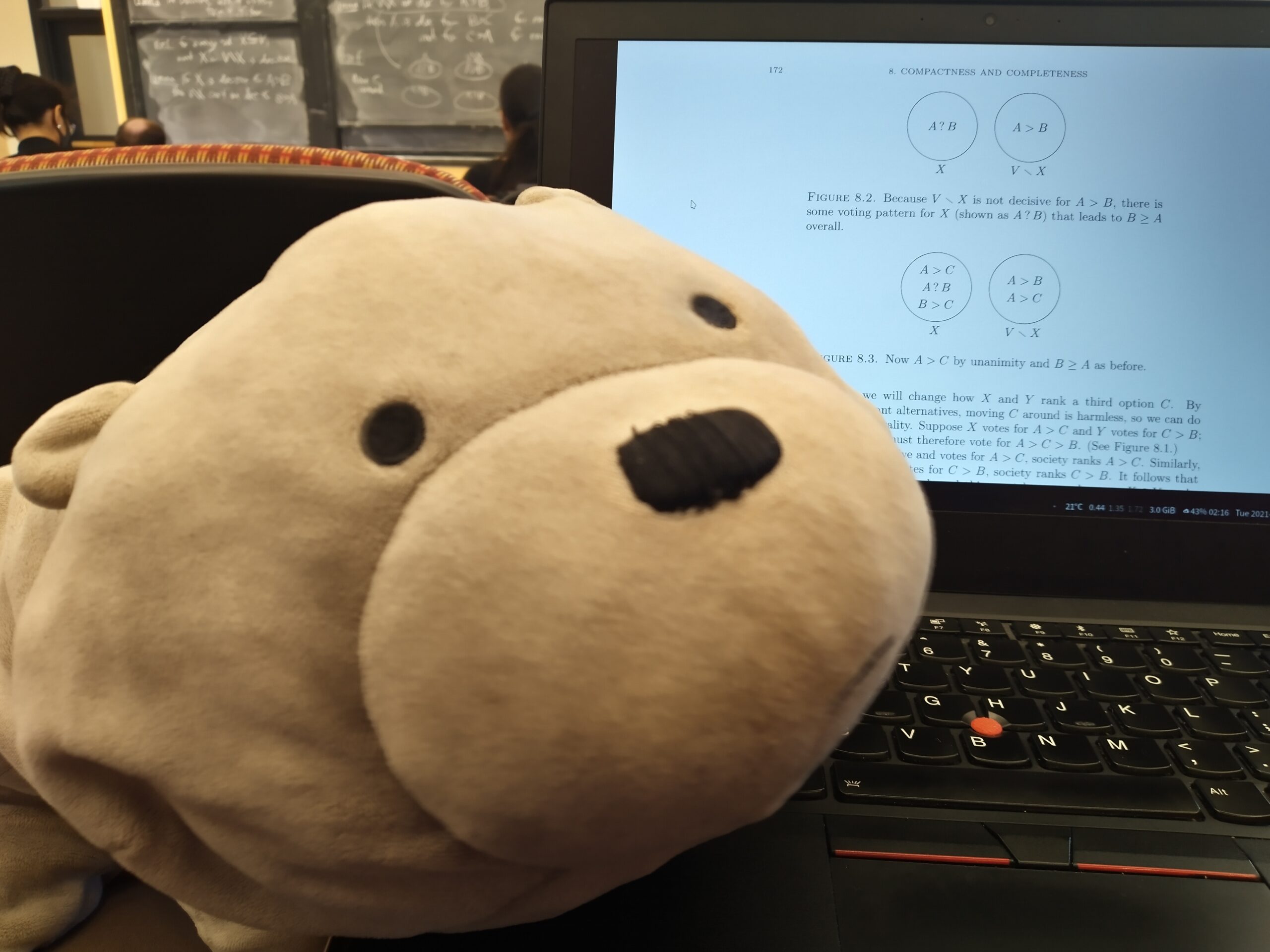 a stuffed toy, ice bear next to a laptop, against a backdrop of a classroom