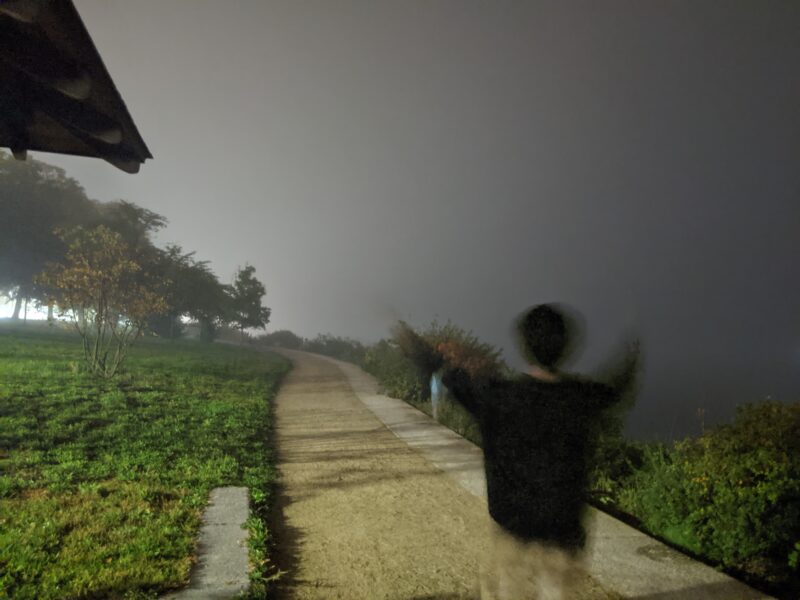 blurry man raising his arms on a path in the fog