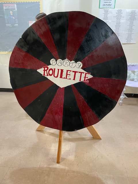 tall wooden wheel, painted black and red, with 'roulette' written in the center