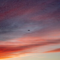 a plane flying through the sunrise