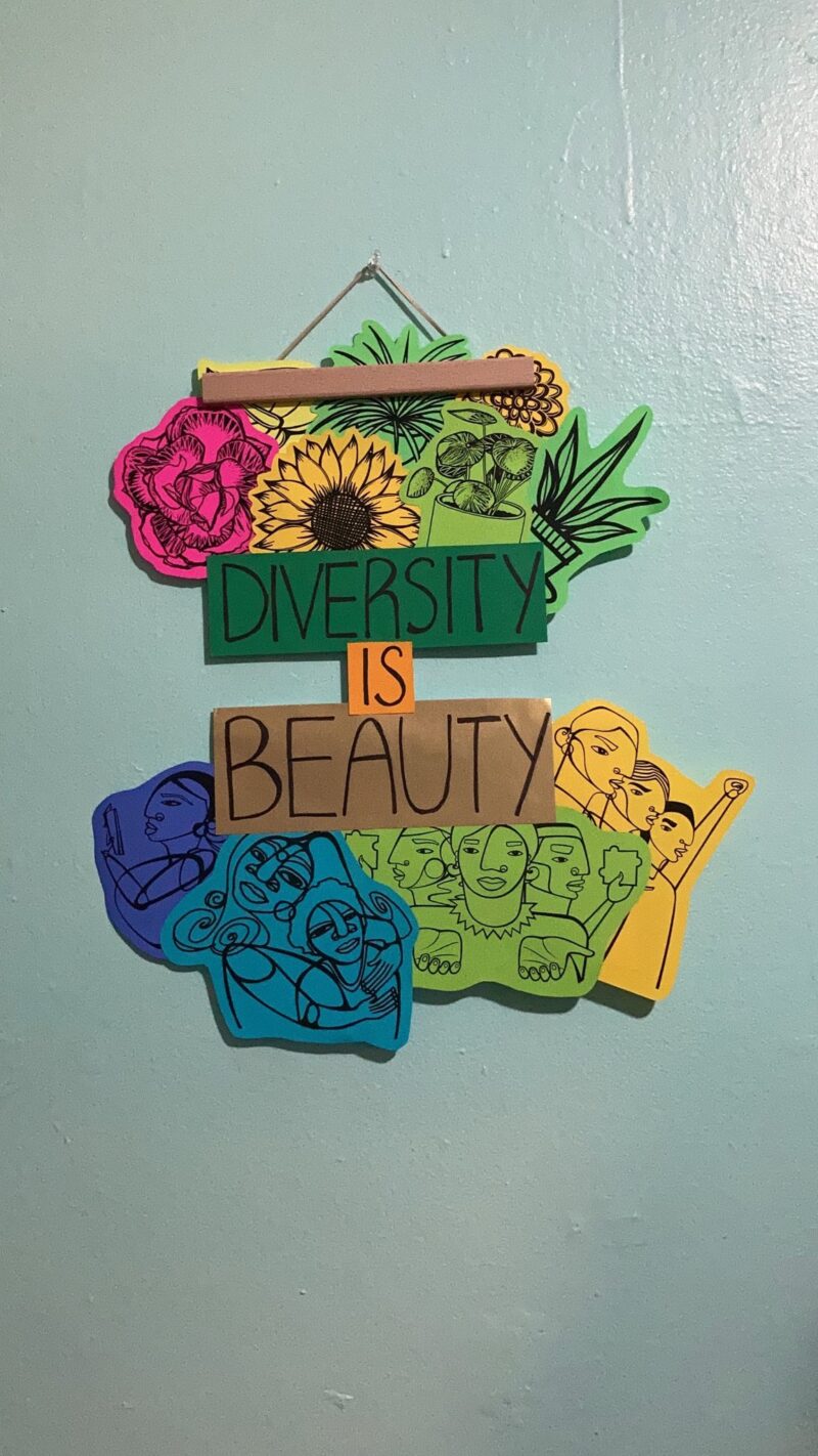 The final version of my poster hanging on my wall. The top third of the poster is lots of different flowers. The middle third says