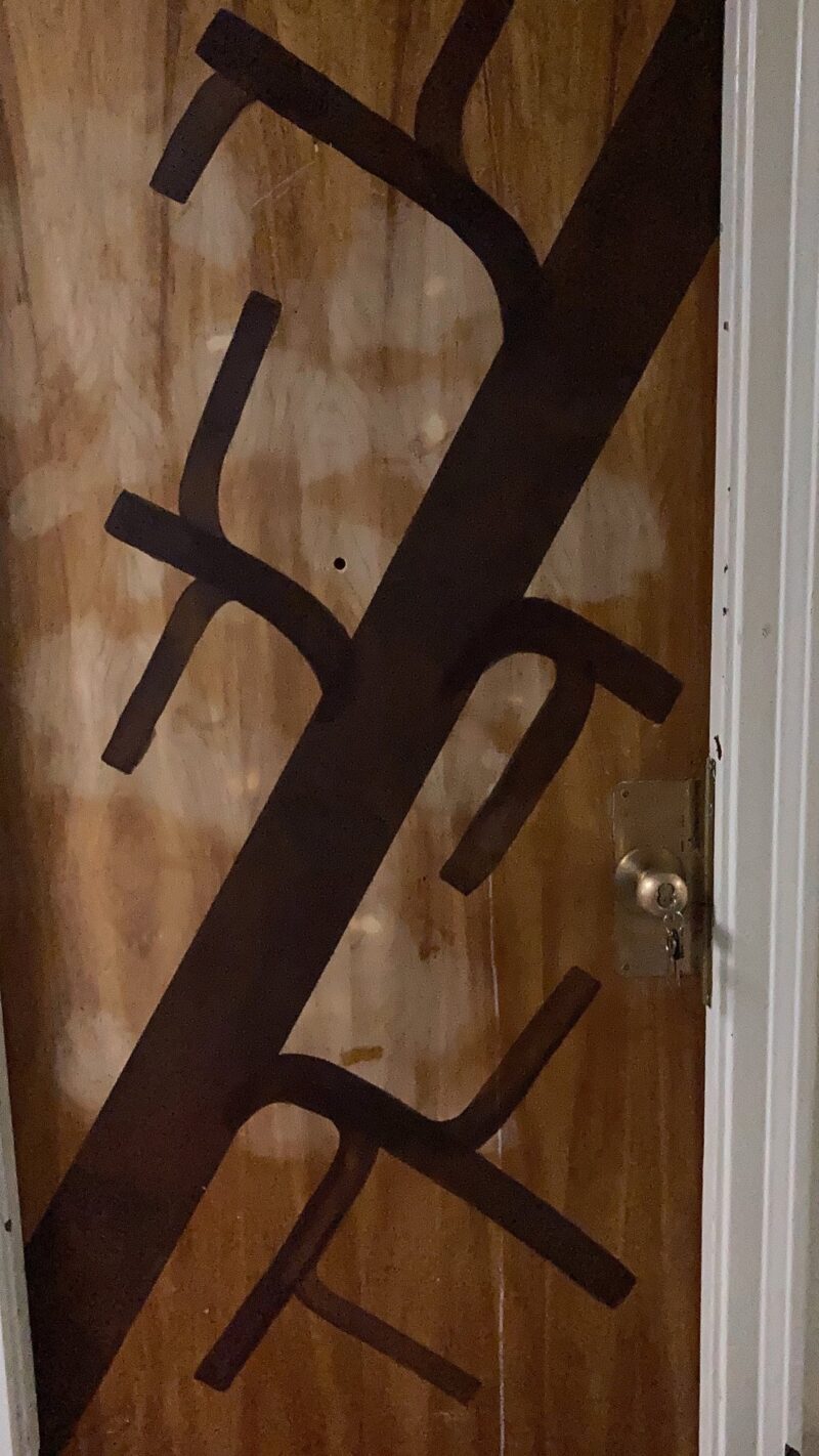 My door after painting. It shows a brown tree trunk with branches coming off of it, in a minimalist geometric style.