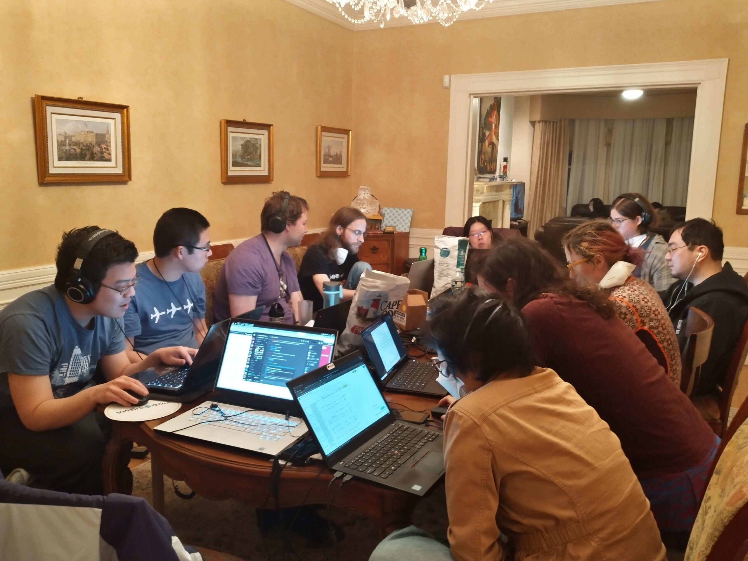 several people gathered around a table with laptops