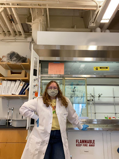 woman in lab coat standing in front of fume hood