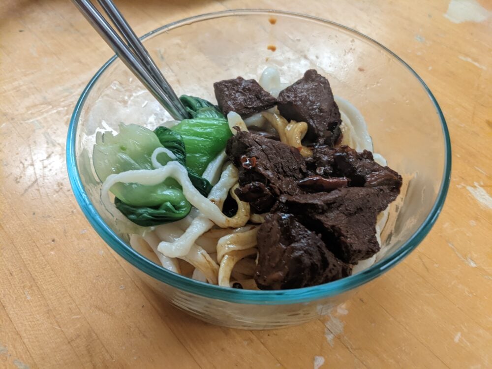 bowl of noodles with meat and vegetables on top