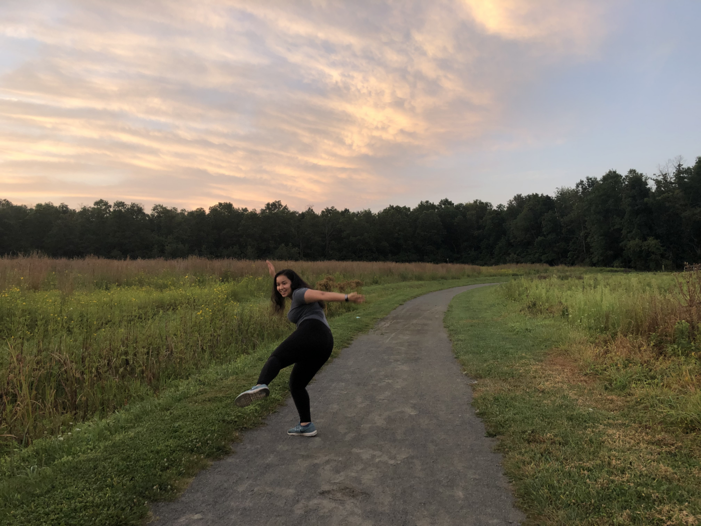 girl posing weirdly in a field during sunrise